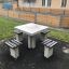 Outdoor concrete Ludo table with four attached seats in a park setting.